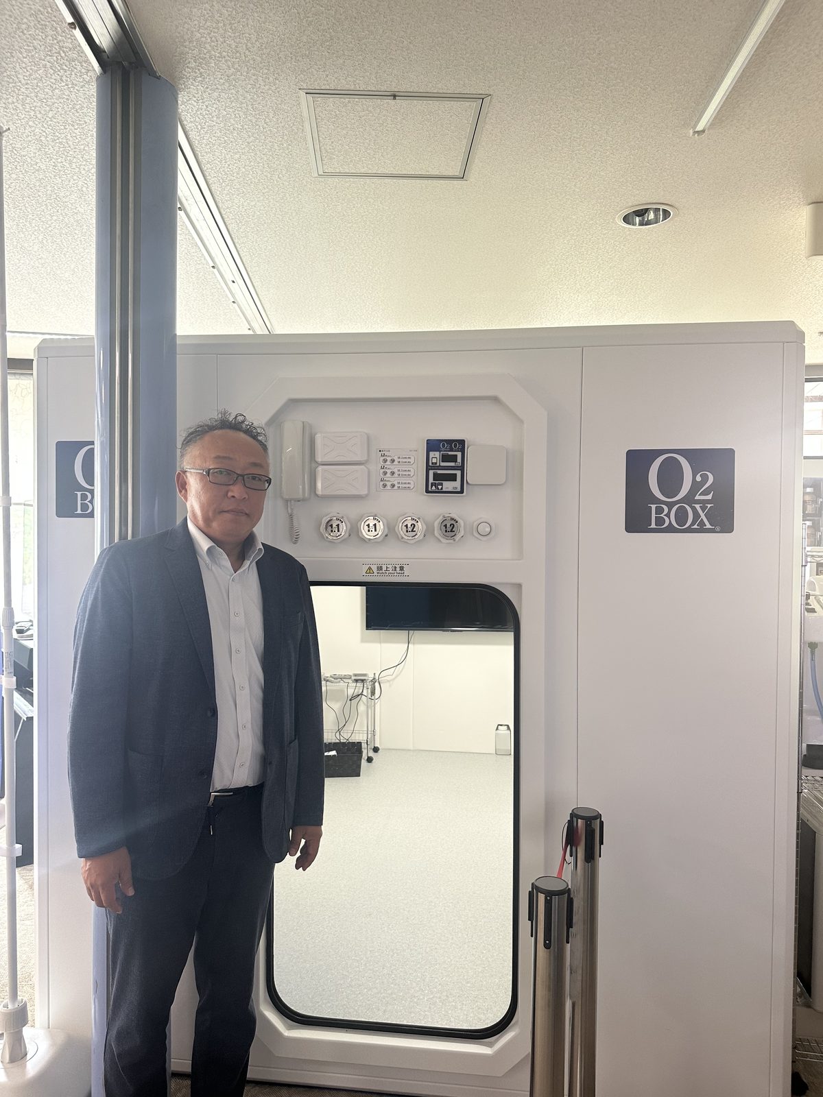 ショールームのO2ボックスの前に立つ代表